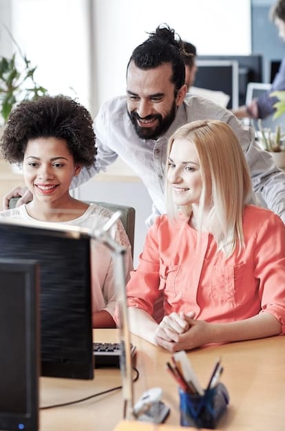 Colleagues smiling and helping each other in a modern office setting, illustrating workplace kindness.