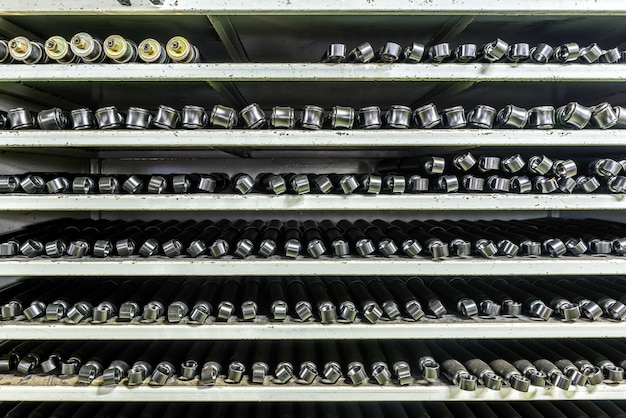 A modern battery storage facility with rows of large, silver battery containers neatly arranged in a secure, outdoor setting. The facility is clean and well-maintained, with advanced monitoring equipment visible.