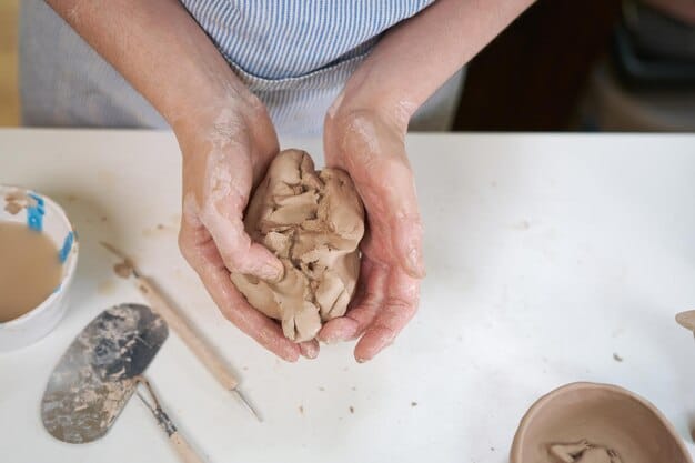 Close-up of a veteran's hands working on a clay sculpture during an art therapy class. The hands show signs of age and experience, conveying a sense of resilience and determination. The clay is molded into an abstract form, representing the emotional journey of the veteran.