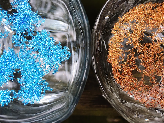 A close-up shot of various microplastics collected in a glass petri dish, showcasing the different colors and textures of the tiny plastic particles. The background is blurred to focus on the microplastics.
