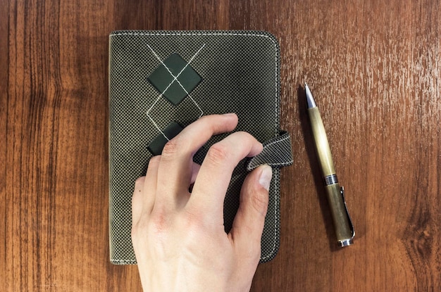 A detailed close-up of a person's hand holding a pen, poised over an open financial planner or ledger, with graphs and numbers visible, symbolizing diligent record-keeping and strategic financial planning.