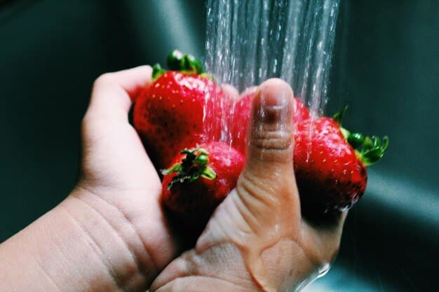 A close-up of a hand washing organic strawberries under running water, emphasizing freshness and cleanliness, with a 