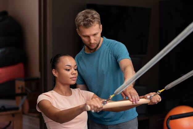 A sports physiotherapist guiding an athlete through a controlled strength training exercise with resistance bands, focusing on correct form and muscular engagement.