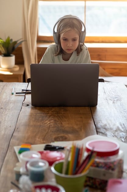 A student wearing headphones, actively engaged in an online class on a laptop, surrounded by educational materials in a well-lit, comfortable home study space. Represents focus and digital learning.