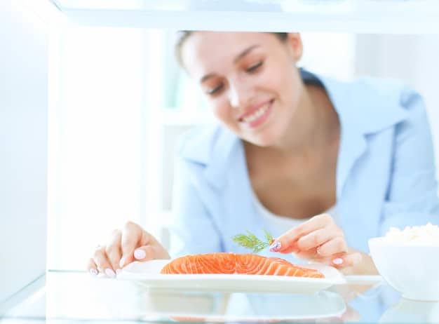 A person enjoying a plate of salmon with various colorful vegetables, sitting next to a sunny window. The food appearance should focus on dietary source of Vitamin D.